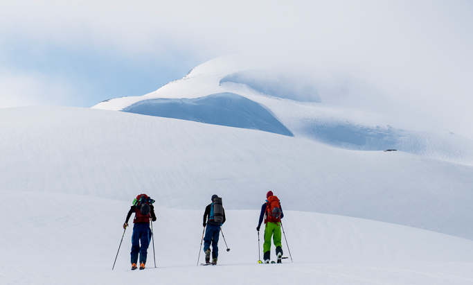 Tre skigåere i snødekt fjell